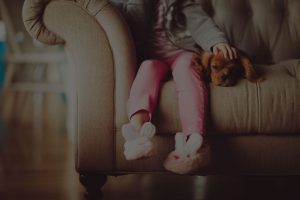 kid sitted on sofa with dog